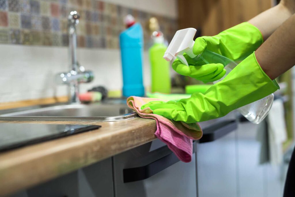 Professional House cleaner wiping kitchen surface - Hetty Keeps Clean